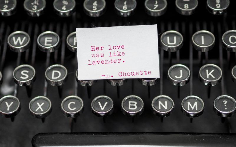 Old fashioned typewriter with note that says: Her love was like lavender —L. Chouette